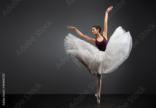 Ballerina. Young graceful woman ballet dancer, dressed in professional outfit, shoes and white weightless skirt is demonstrating dancing skill. Beauty of classic ballet.