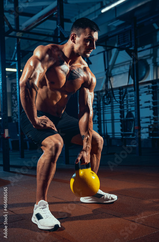 One muscled athlete, bodybuilder workouts alone at sport gym, indoors. Concept of sport, activity, healthy lifestyle
