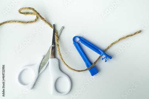 sterile scissors and umbilical cord clamp with a rope on white background. Birth at home, cutting umbilical cord concept.