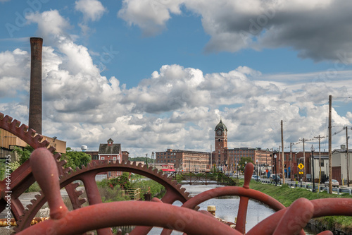 Red industrial gears with nineteenth century brick mill building in background