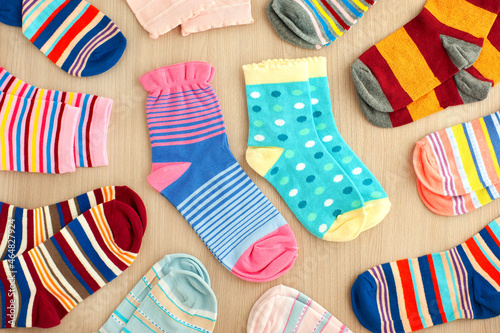 Lots of bright colorful socks. Socks on a wooden background. Multicolored socks for cold seasons.