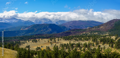 Estes Park Panoramic Landscape Rocky Mountains in snow and clouds with valley, aspen and evergreen trees in autumn.