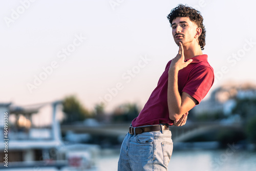 Portrait of an effeminate young man with modern look next to an urban river