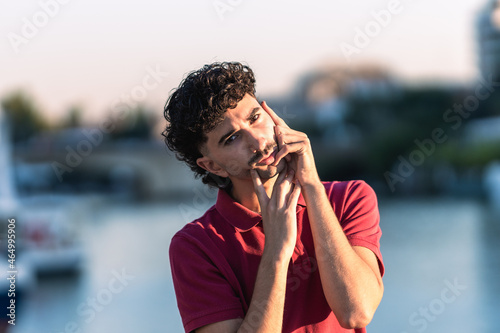 Young caucasian man with modern hair cut doing an effeminate gesture outdoors
