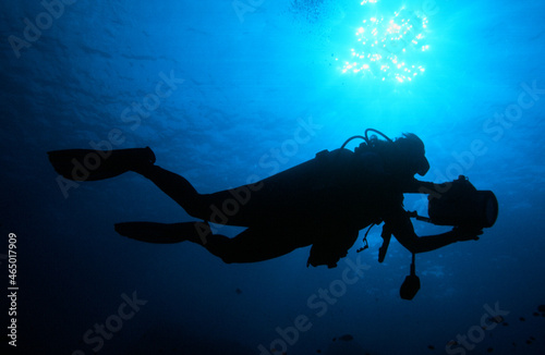 A Scuba Diver Exploring the Ocean Silhouetted by the Sun with a Video Camera