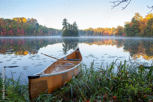 Yellow canoe on shore of beautiful lake with island in northern Minnesota at dawn