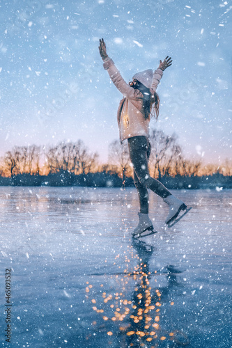 a girl on skates spinning on open ice under a snowfall. active winter holidays