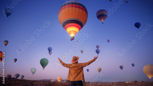 Man traveler arms outstretched standing to sky hot air balloons in Cappadocia, Turkey. Concept freedom lifestyle sunrise banner.