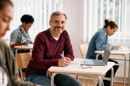 Happy mature student learns in classroom and looks at camera.