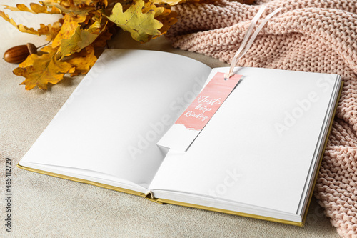 Blank open book with bookmark and oak leaves on light background