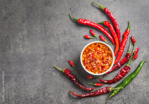 Chili oil sauce chili peppers flakes in oil dark background copy space. Spicy condiment.