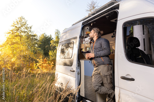 Man and his his camper van standing in an autumn scenery