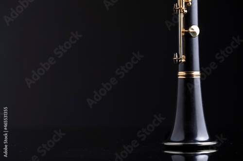 A bell of a clarinet on a reflective surface with a dark background