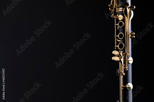 Part of a clarinet with gold plated keys on a black background. A woodwind instrument common to classical music.