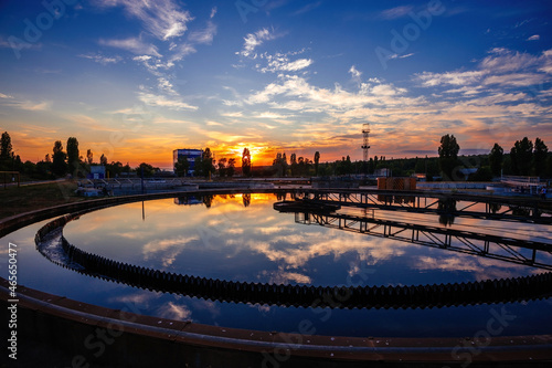 Modern sewage treatment plant. Round wastewater purification tank at sunset
