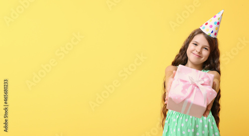 Little girl with birthday gift on color background