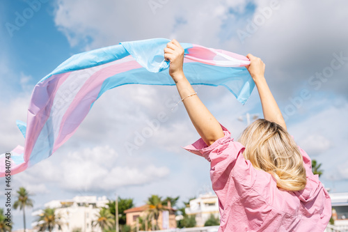 Woman with fluttering transgender lgtbi flag on windy day