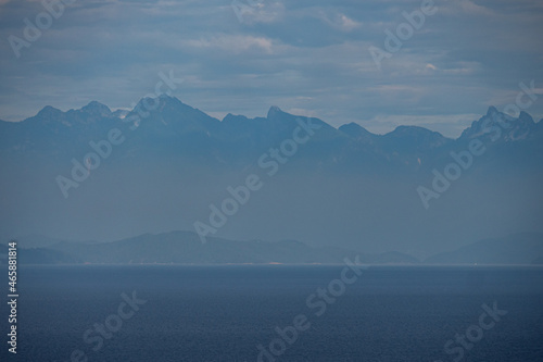 mountain range over the horizon by the ocean cover in hazy atmosphere near dawn
