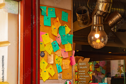 kolorowe notatki z przypomnieniami i notatkami przy wejściu do zabytkowej kawiarni młodzieżowej w Europie ogromne ciepłe lampy metalowa folia i rury w stylu grunge loft