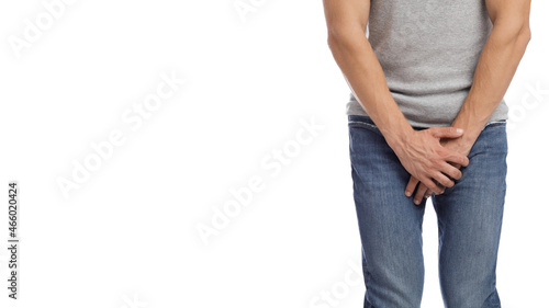 Cropped millennial european muscular male suffering from groin pain, presses hand to crotch