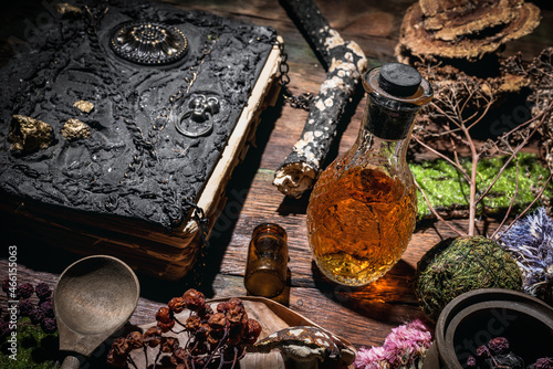 Concept of magic book, dry herb and magic potion on the wooden table background.