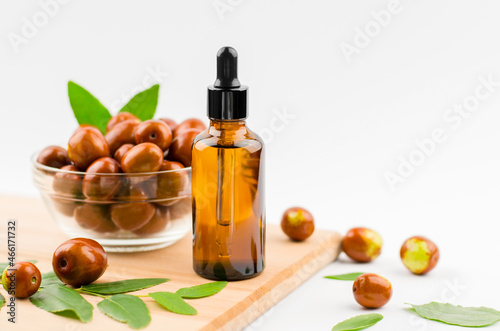 Jojoba oil in a bottle with a dropper on a wooden table with ripe jojoba fruits. Chinese Date Oil and Fruit
