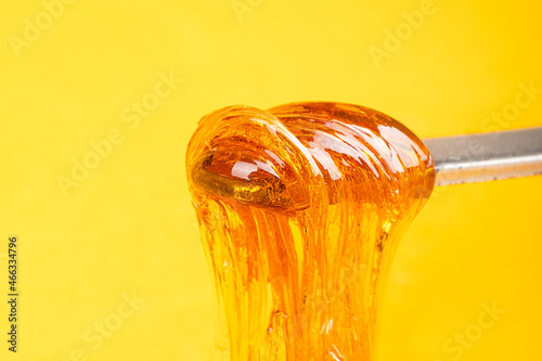 amber yellow cannabis wax concentrate dripping from the dabbing tool close-up