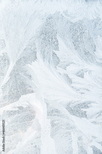 Winter background. Frost pattern. Cold weather. Christmas coming. Decorative abstract natural ice crystals on frozen white window glass texture.