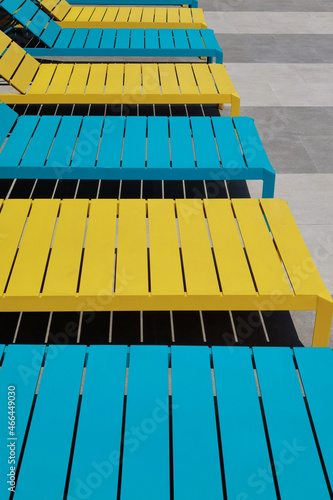 close up view of wooden sun lounger chair by the side of a swimming pool 