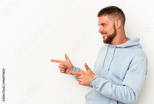 Young caucasian man with diastema isolated on white background points with thumb finger away, laughing and carefree.