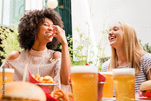 Two attractive vivacious young women enjoying snacks and a drink