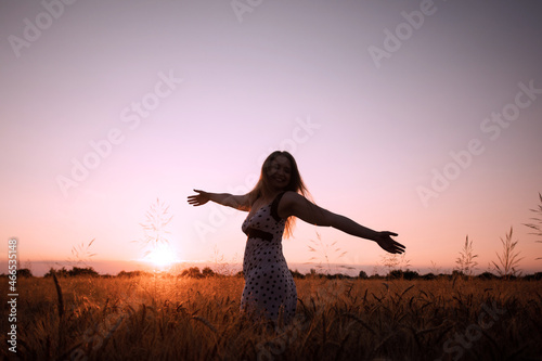 Peaceful woman wellcoming the rising sun in field