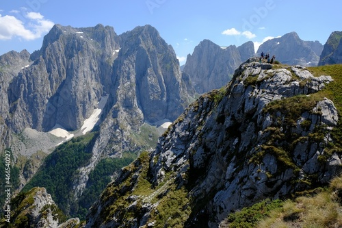 Mountain views during trekking along beautiful tourist loop on Montenegrin side of Prokletije Mountains: Volusnica (1879 m) - Taljanka (2018 m) - Popadija (2057 m). Silhouettes of people on ridge.