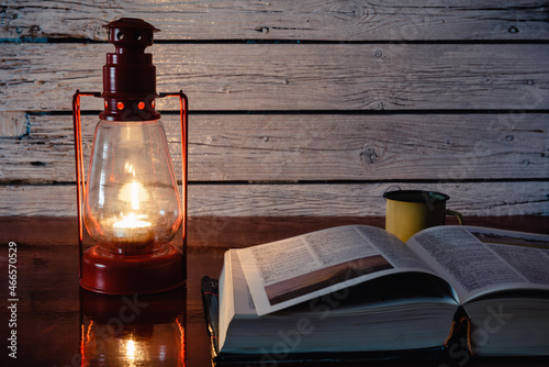 Lámpara de vela antigua junto a un libro abierto, concepto de apagón eléctrico