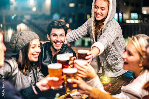 Happy people drinking beer at brewery bar out doors - Multicultural life style concept with genuine friends enjoying time together at open air restaurant patio - Vivid filter with focus on guy