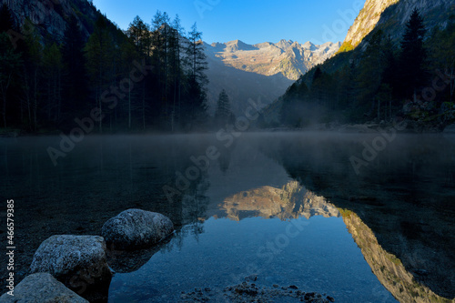 Fog from the lake discover mountain reflection. Reflection of Val Masino mountain range in the Bidet Della Contessa lake.