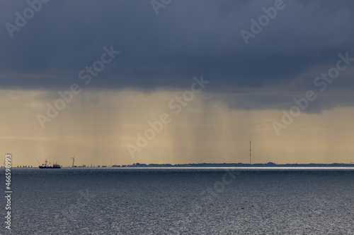 Landscape view of sea in cloudy day, Raining above the the ocean, Overview of Dutch north sea coastline with dark grey clouds from mainland in Texel island, North Holland, Netherlands.