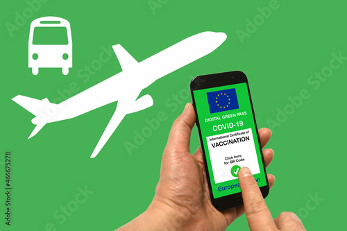 A man's hand holds a smartphone with the digital green pass for Covid-19 of the European Union on a green background with white bus and airplane symbols. safe concept
