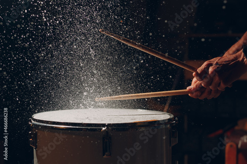 Close up drum sticks drumming hit beat rhythm on drum surface with splash water drops in air