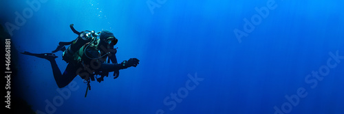 Technical scuba diver in a horizontal position with sun rays blue background