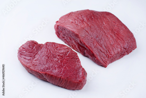 Raw dry aged bison beef rump steak slices offered as close-up on white background with copy space - free-form select