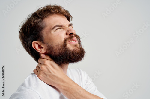 man in a white t-shirt stress medicine pain in the neck light background
