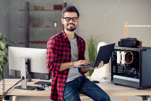 Portrait of attractive qualified guy senior designer dev ops manager using laptop designing at office work place station indoor