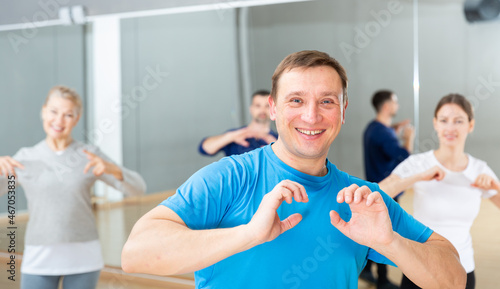 Portrait of cheerful adult man enjoying vigorous dances in modern dance studio