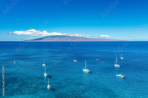 Aerial shot of sailboats in Lahaina, Maui, Hawaii with teal water on calm blue sky day