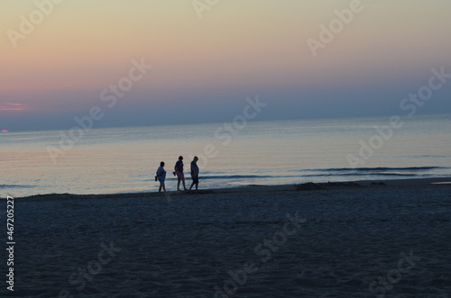 Troje ludzi na plaży po zachodzie słońca, spokój, Bałtyk