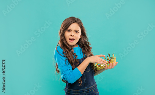 confused kid with curly hair in princess crown on blue background, selfishness