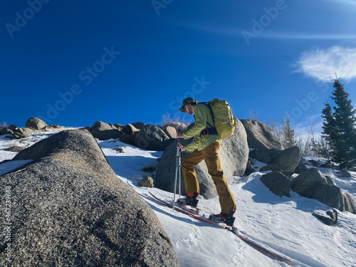 Man backcountry skiing in a rocky area on a sunny day