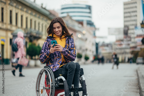 Woman in wheelchair using a smartphone while out in the city