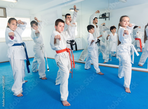 Young children practicing a new moves with coach during karate class..